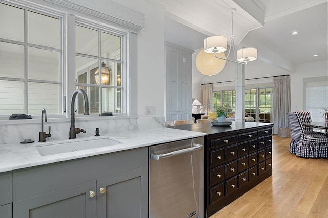 interior space with light stone countertops, light wood-style flooring, dishwasher, a sink, and hanging light fixtures