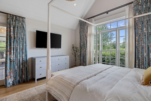 bedroom with multiple windows, wood finished floors, and vaulted ceiling