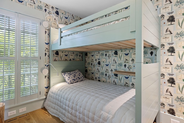 bedroom featuring wallpapered walls, wood finished floors, and visible vents
