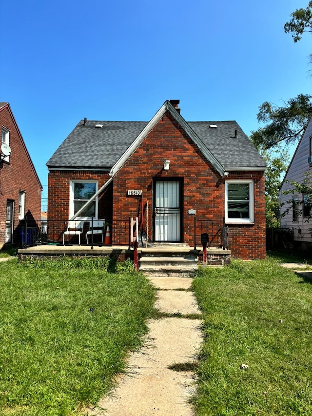 back of house featuring a yard, brick siding, and roof with shingles