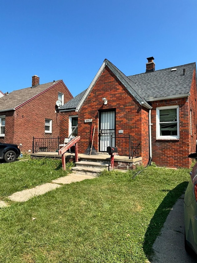 back of house featuring a chimney, a yard, a shingled roof, and brick siding