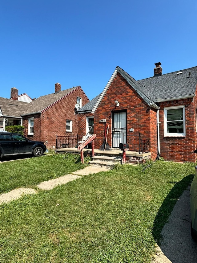 exterior space with brick siding, a chimney, and a front lawn