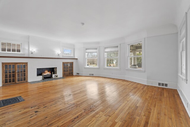 250 Alger St, Detroit, MI 48202 - unfurnished living room with visible vents, light wood-type flooring, baseboards, and a brick fireplace