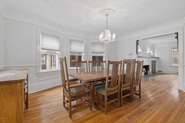 250 Alger St, Detroit, MI 48202 - dining area featuring light wood-style floors, an inviting chandelier, and a fireplace