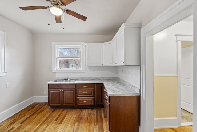 250 Alger St, Detroit, MI 48202 - kitchen featuring white cabinets, a sink, light countertops, backsplash, and light wood-style flooring