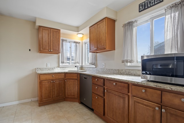kitchen featuring brown cabinetry, appliances with stainless steel finishes, and light stone countertops