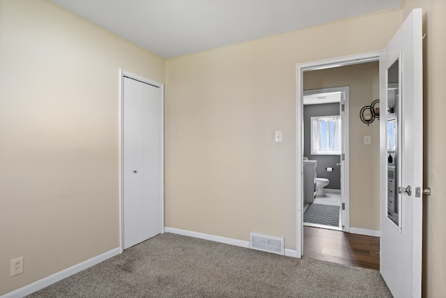 unfurnished bedroom with a closet, carpet flooring, visible vents, and baseboards