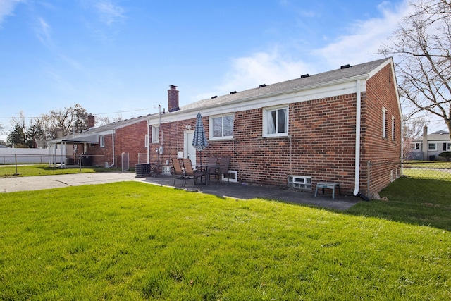 rear view of house featuring a lawn, a chimney, fence, a patio, and brick siding