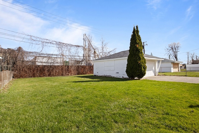view of yard featuring driveway, an outbuilding, a garage, and fence