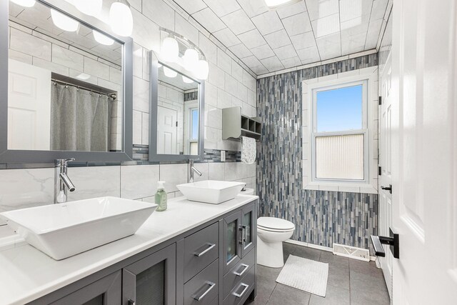 bathroom featuring tile walls, a sink, and toilet
