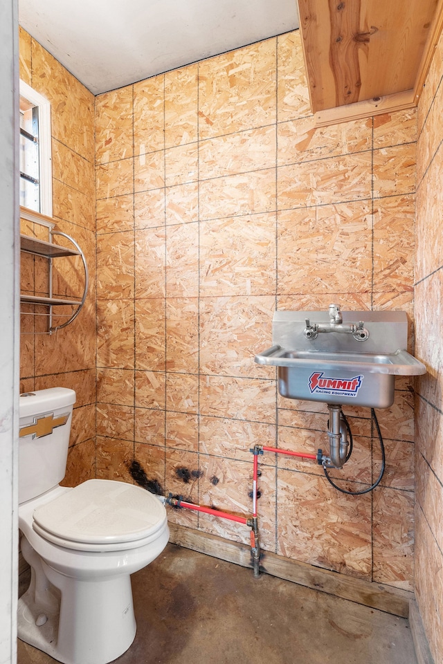 half bathroom featuring toilet, concrete flooring, and a sink