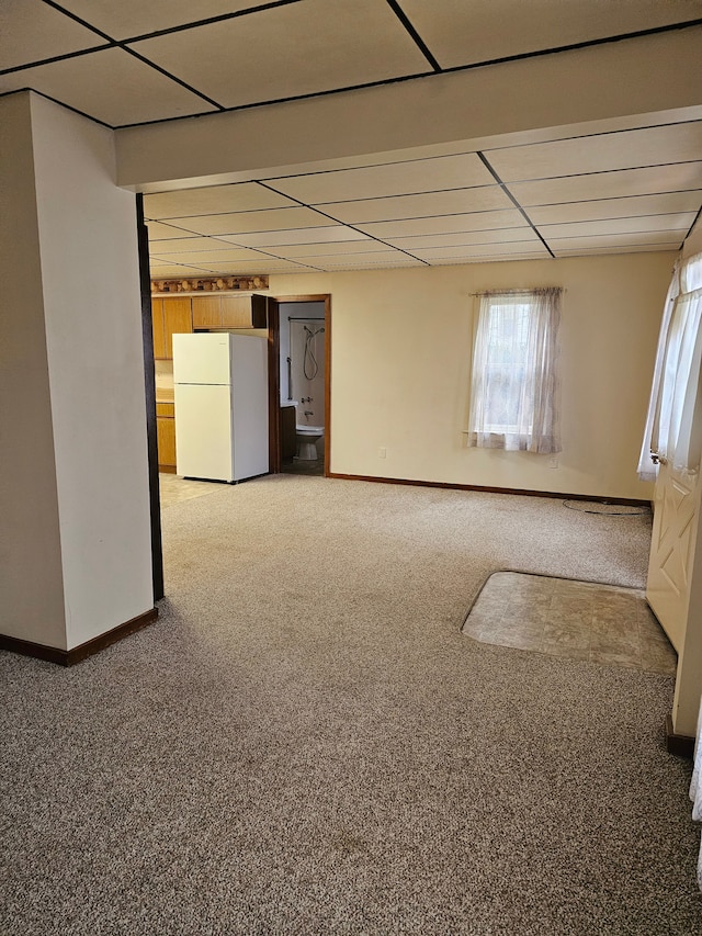 basement with carpet flooring, baseboards, and freestanding refrigerator