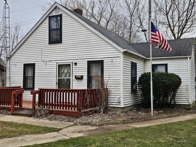 back of house featuring a chimney and a shingled roof