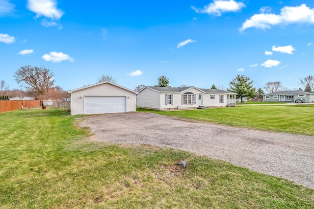 view of front of house featuring an outbuilding, a detached garage, fence, and a front lawn