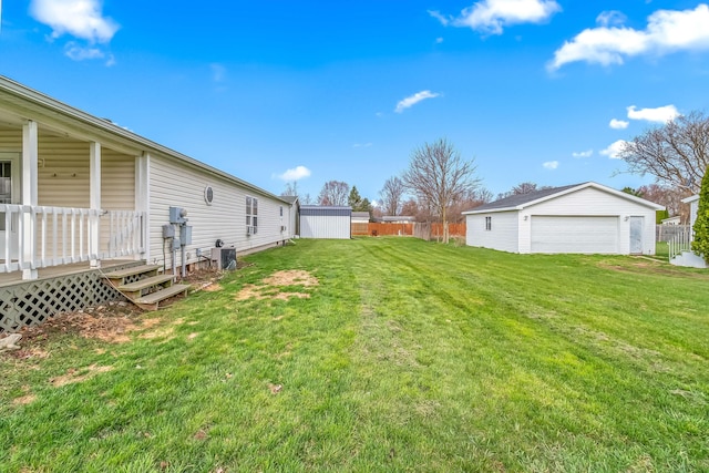 view of yard featuring an outbuilding, a detached garage, and fence