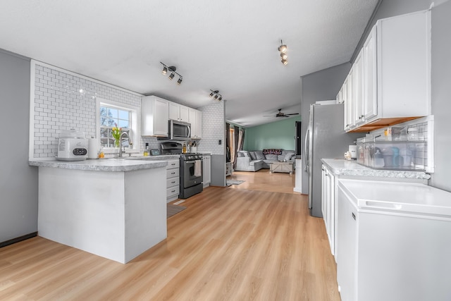 kitchen featuring light wood-type flooring, a ceiling fan, white cabinets, decorative backsplash, and stainless steel appliances