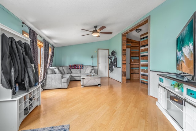 living area featuring a textured ceiling, wood finished floors, a ceiling fan, and vaulted ceiling