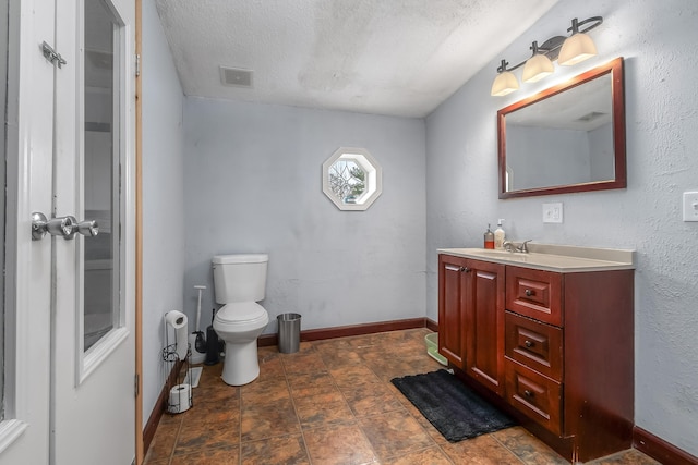 bathroom with a textured ceiling, vanity, visible vents, toilet, and baseboards