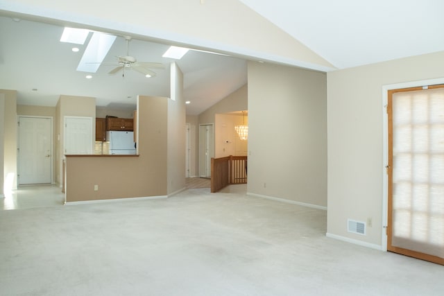 unfurnished living room with baseboards, lofted ceiling with skylight, visible vents, and light colored carpet