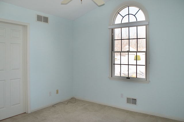 spare room with visible vents, lofted ceiling, a ceiling fan, and carpet floors