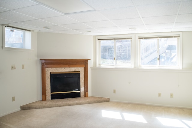 unfurnished living room with carpet, a high end fireplace, a healthy amount of sunlight, and a paneled ceiling