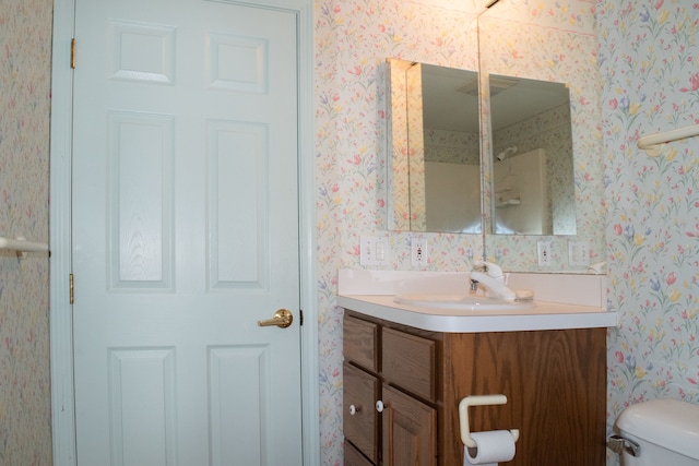 bathroom featuring vanity, toilet, and wallpapered walls