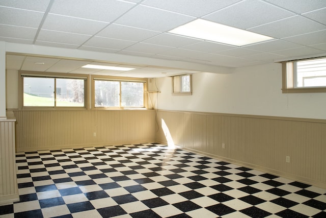 basement with tile patterned floors, a drop ceiling, and wainscoting