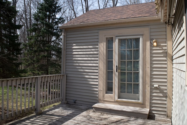 exterior space featuring a shingled roof and a deck