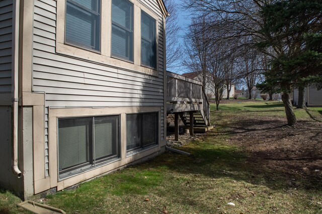 view of side of property with stairway, a deck, and a lawn