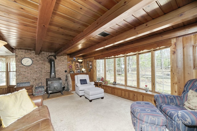 carpeted living area featuring brick wall, a wood stove, wood ceiling, beamed ceiling, and wood walls