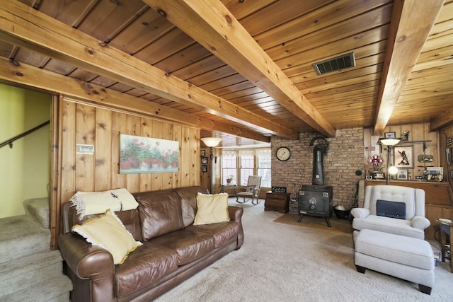 living area featuring a wood stove, carpet, wood ceiling, stairs, and beam ceiling