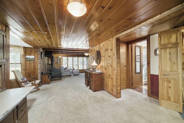 interior space featuring wood walls, a wood stove, wooden ceiling, and light carpet