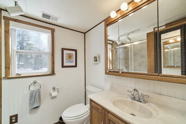 full bathroom featuring toilet, a shower with shower door, vanity, and visible vents