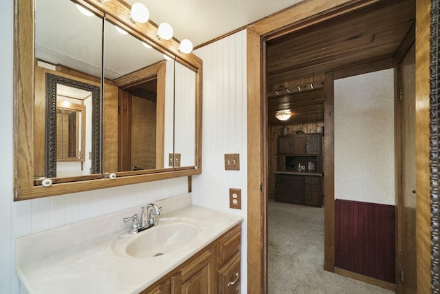 bathroom featuring wooden walls, vanity, and wainscoting