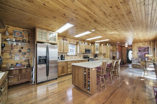 kitchen featuring a sink, appliances with stainless steel finishes, wood finished floors, and light countertops