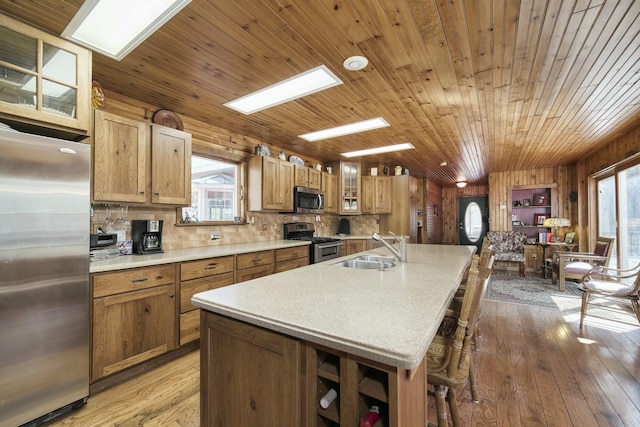 kitchen with glass insert cabinets, light wood-style flooring, a sink, light countertops, and stainless steel appliances