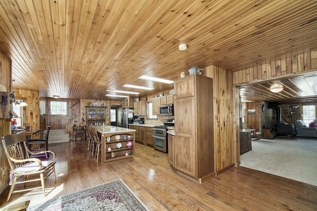 kitchen featuring light wood-style flooring, light countertops, open shelves, a wood stove, and appliances with stainless steel finishes