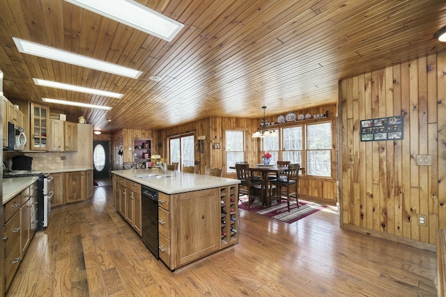 kitchen featuring glass insert cabinets, light countertops, stainless steel appliances, hardwood / wood-style flooring, and a sink