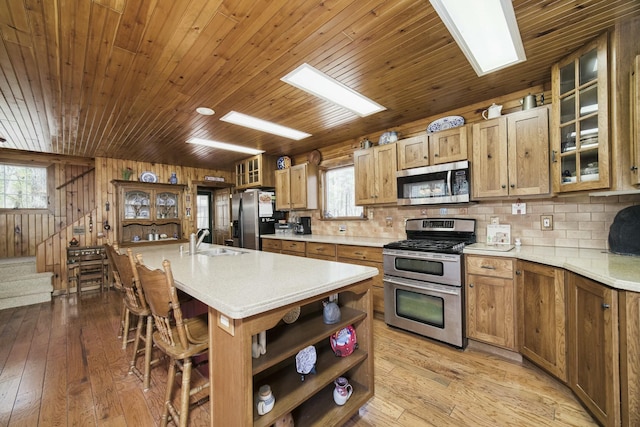kitchen featuring a sink, open shelves, light wood finished floors, and stainless steel appliances