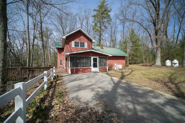 rustic home with a front lawn, fence, a sunroom, and aphalt driveway