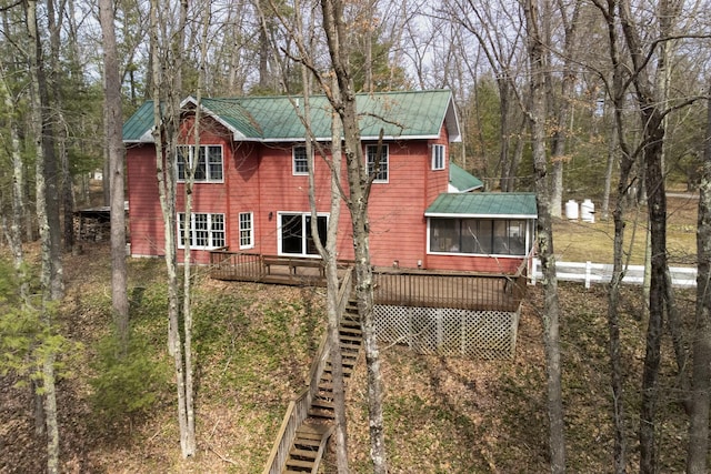 back of property with a wooden deck, metal roof, a sunroom, and stairs