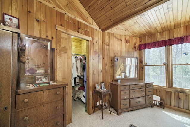 bedroom with wooden ceiling, a walk in closet, vaulted ceiling, wood walls, and light carpet