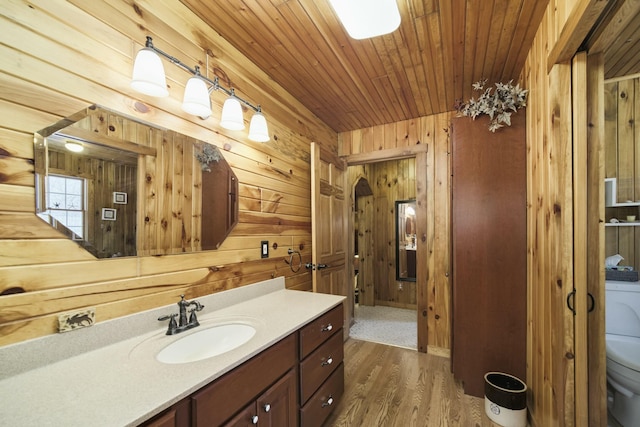 bathroom featuring wooden ceiling, toilet, vanity, wood finished floors, and wood walls