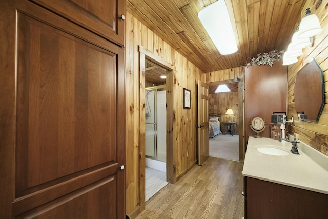 full bath with vanity, wooden ceiling, wood finished floors, a stall shower, and wooden walls