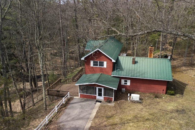 chalet / cabin featuring metal roof, a deck, a forest view, and a chimney