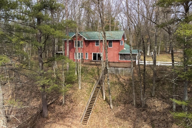 rear view of house featuring stairway, a deck, a view of trees, and metal roof