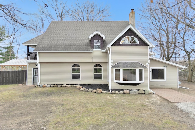 3628 Ford Ave, Jackson, MI 49203 - back of property with a chimney, fence, a shingled roof, a balcony, and a lawn