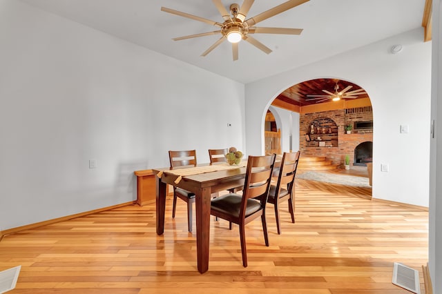 3628 Ford Ave, Jackson, MI 49203 - dining space featuring arched walkways, light wood-style flooring, a brick fireplace, and ceiling fan