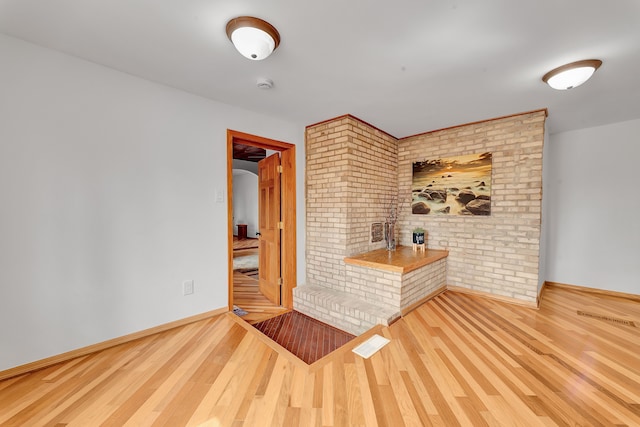 3628 Ford Ave, Jackson, MI 49203 - spare room featuring brick wall, baseboards, and wood finished floors