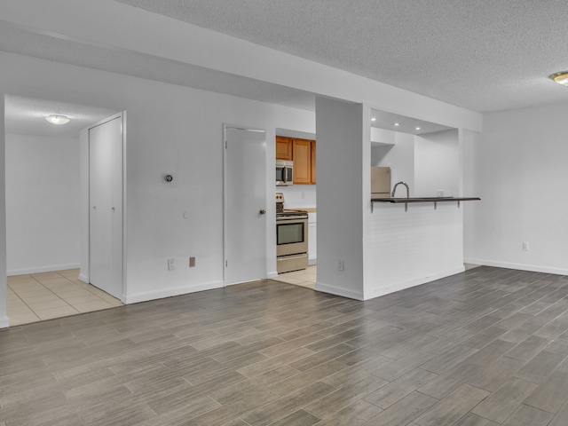 2401 Packard St Unit 31D, Ann Arbor, MI 48104 - unfurnished living room with a textured ceiling, wood finished floors, and baseboards